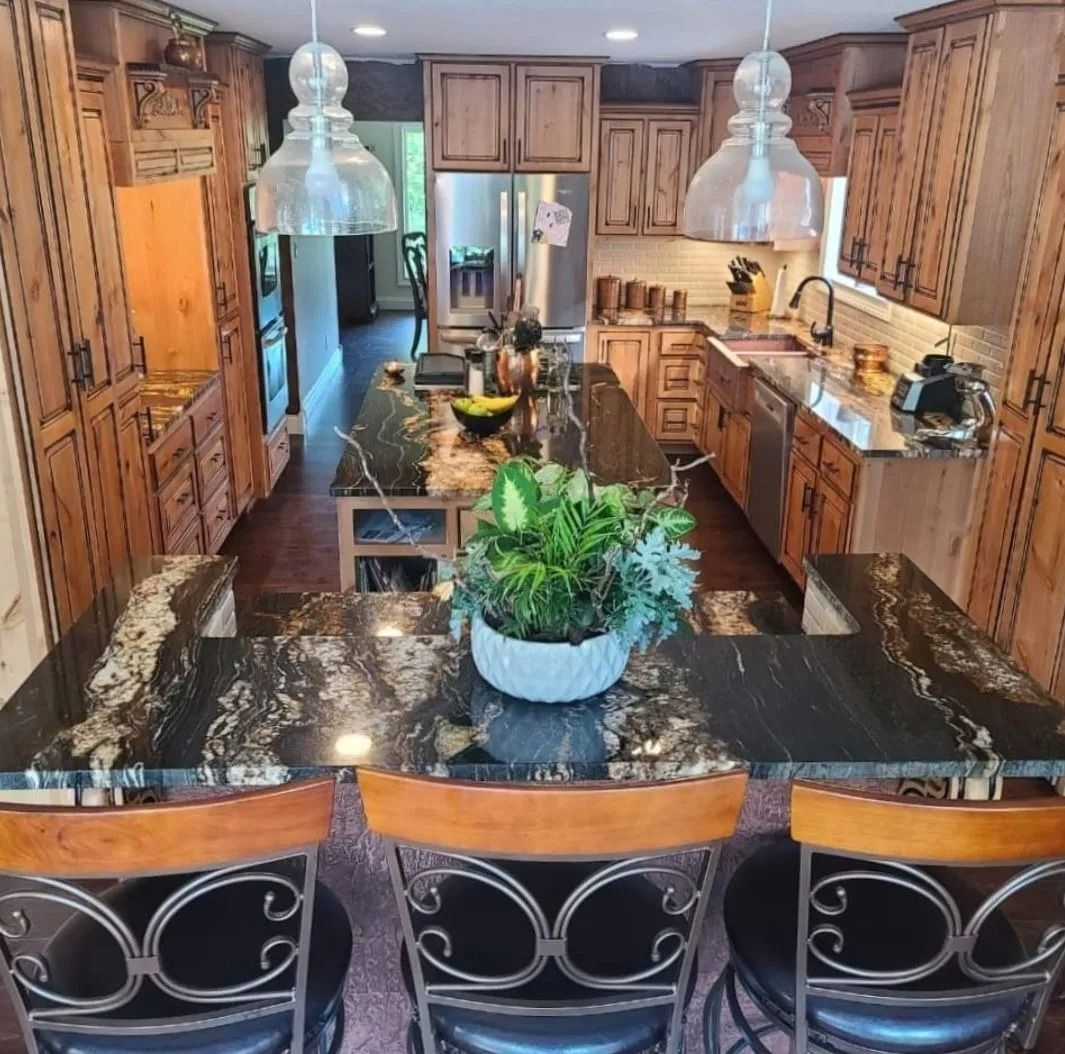 Kitchen with dark granite countertops, wooden cabinets, and three bar stools.