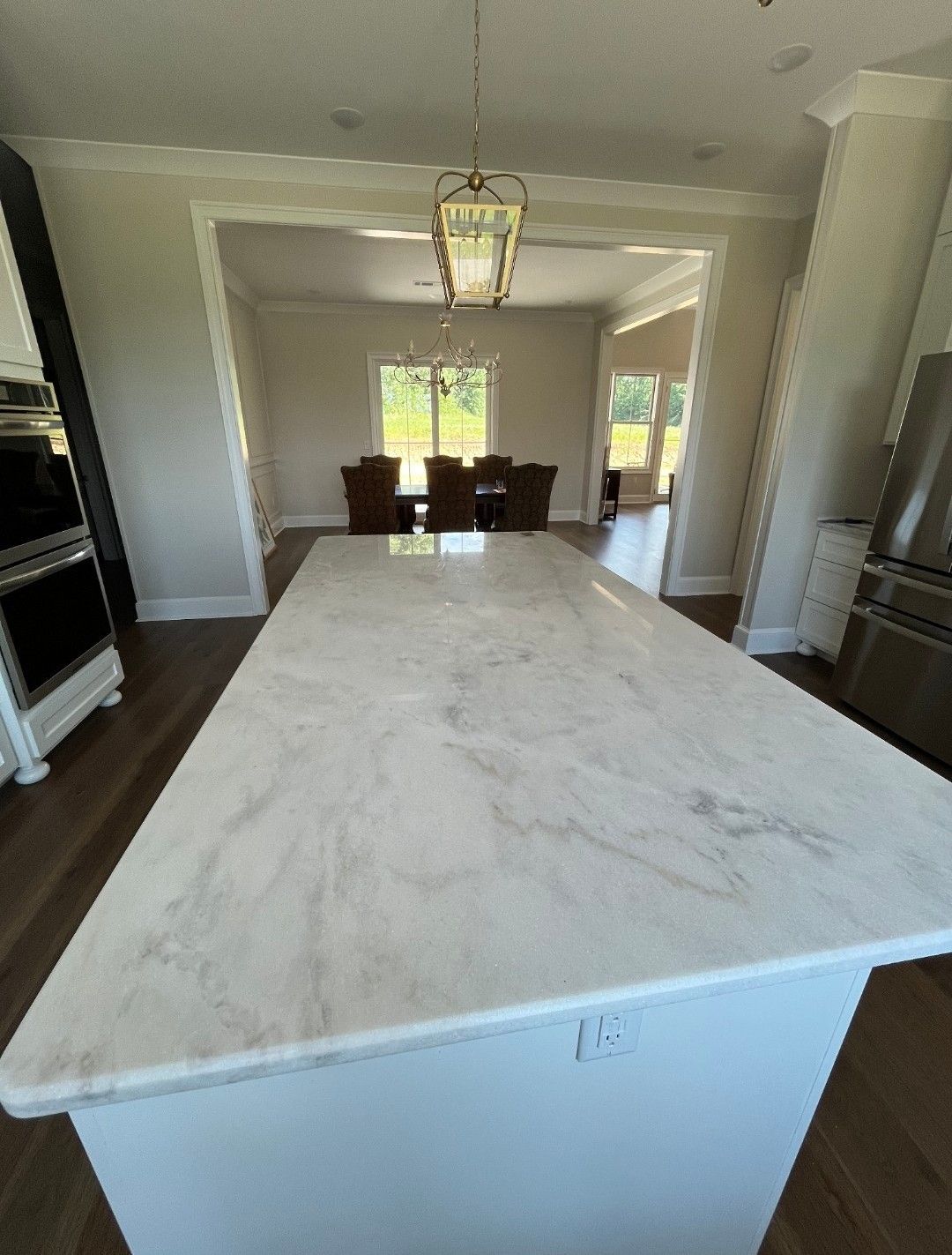 Bright, modern kitchen with a large white marble island, open to a dining area.