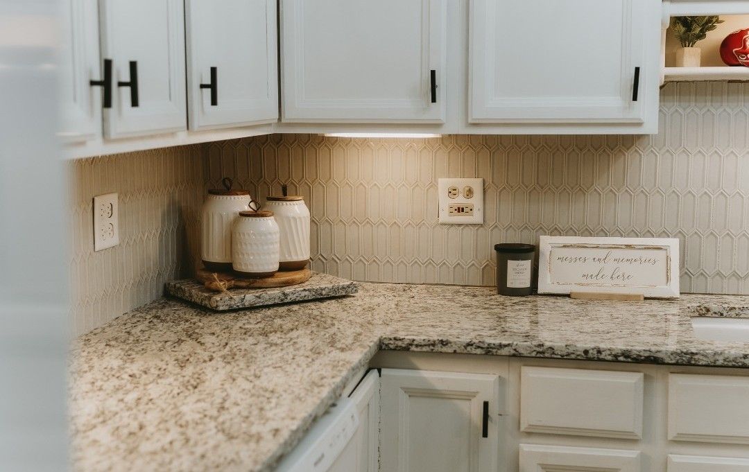 White kitchen corner with countertops, cabinets, and decorative jars on a wooden tray.
