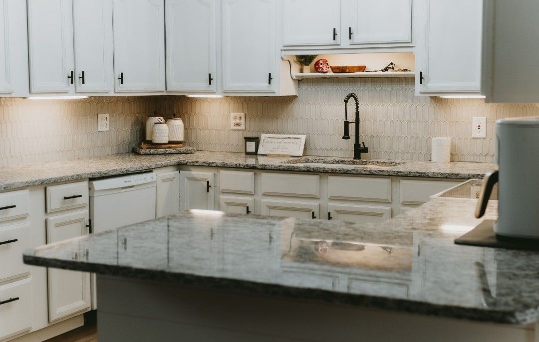 White kitchen with granite countertops and black faucet.