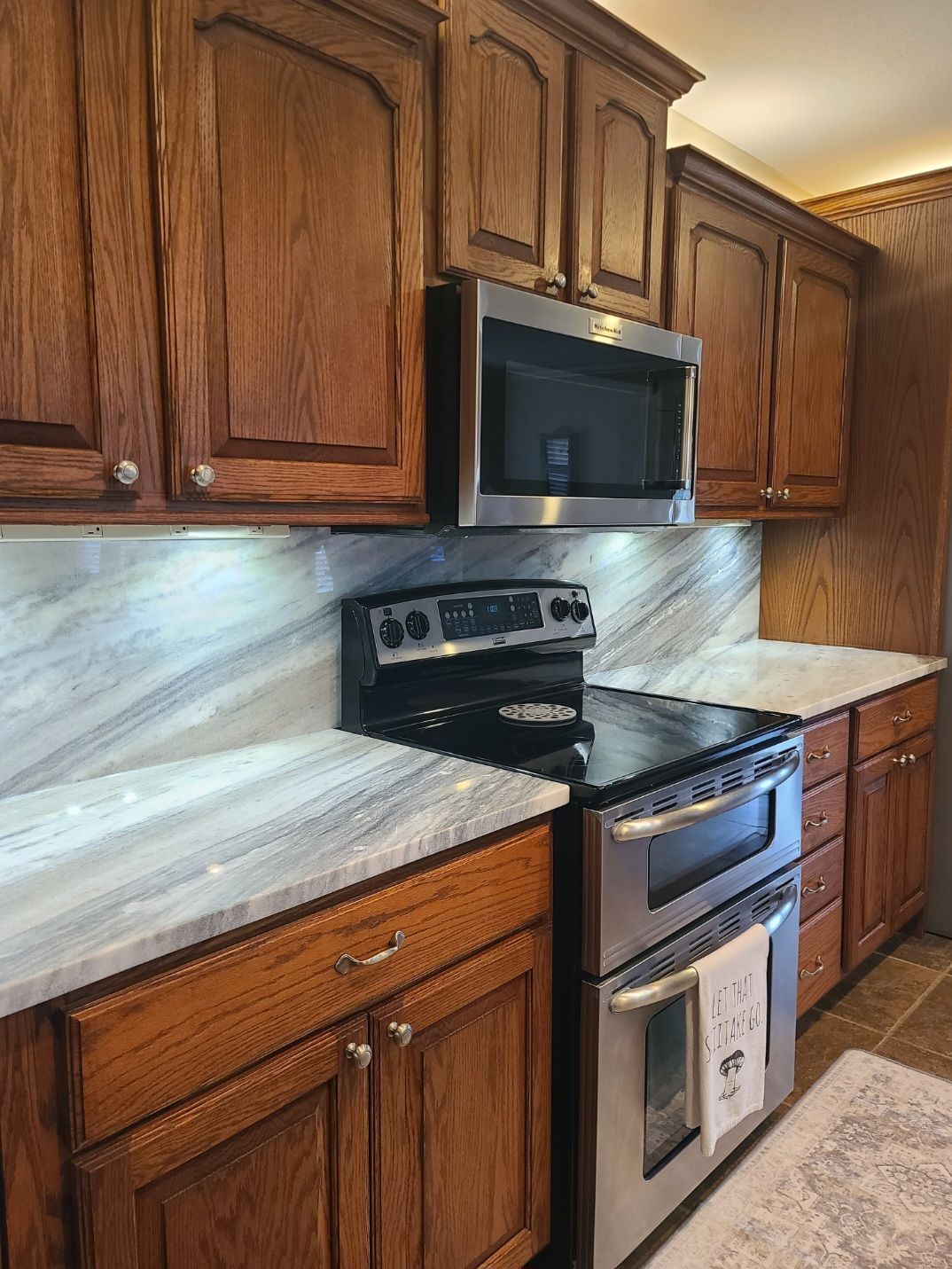 Kitchen with brown cabinets, stainless steel appliances, and marble-look countertops.