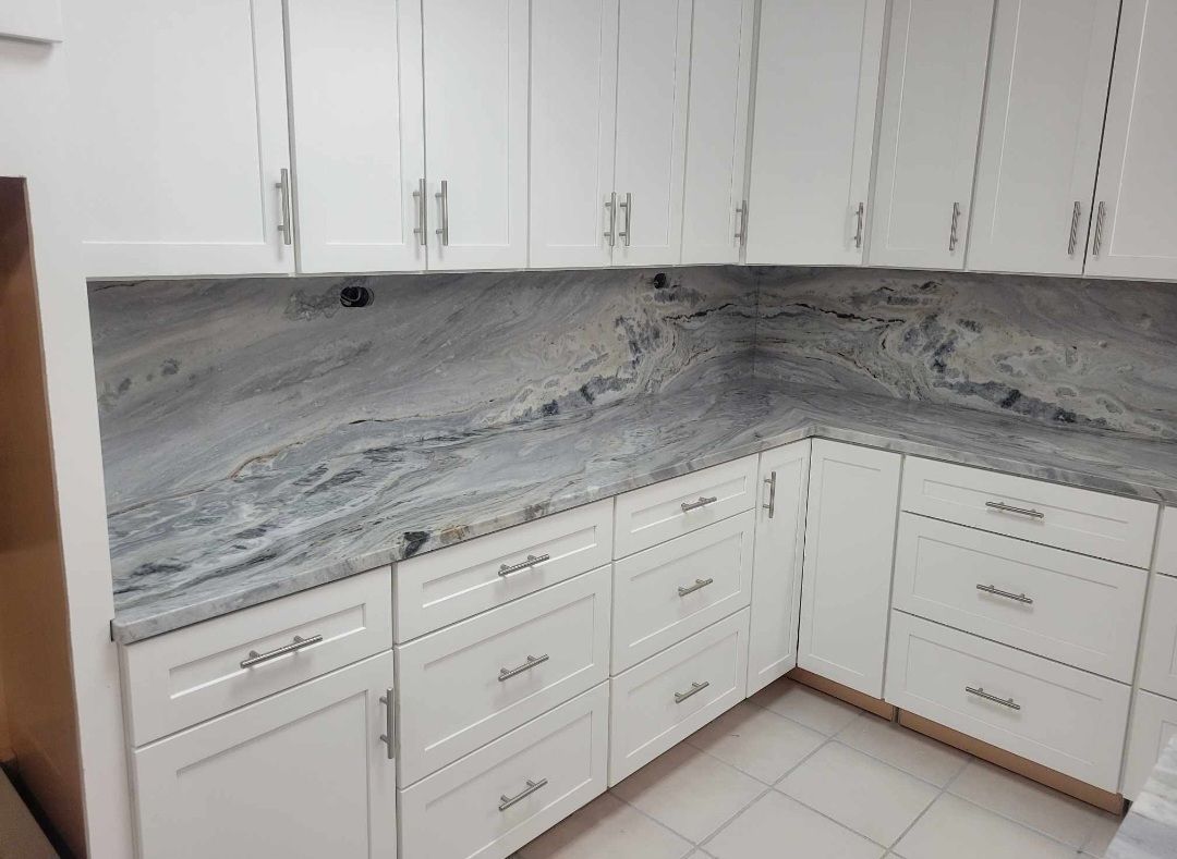 White kitchen cabinets with gray and white patterned countertops.
