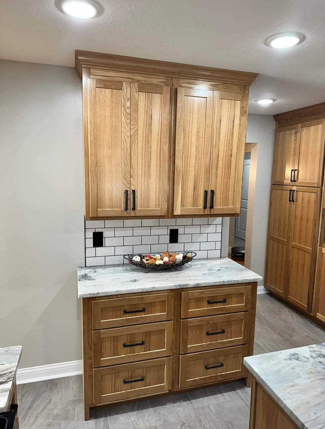 Kitchen cabinetry with light wood, granite countertop, white tile backsplash.