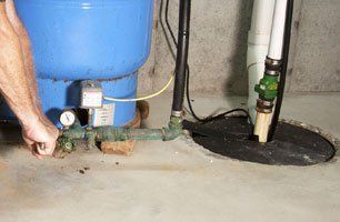 A man is fixing a water pump in a basement.