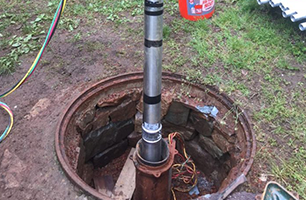 A manhole cover with a metal pipe sticking out of it.