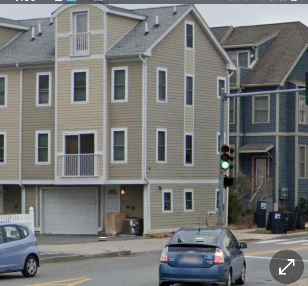 Street scene with beige houses, parked cars, and a traffic light at an intersection