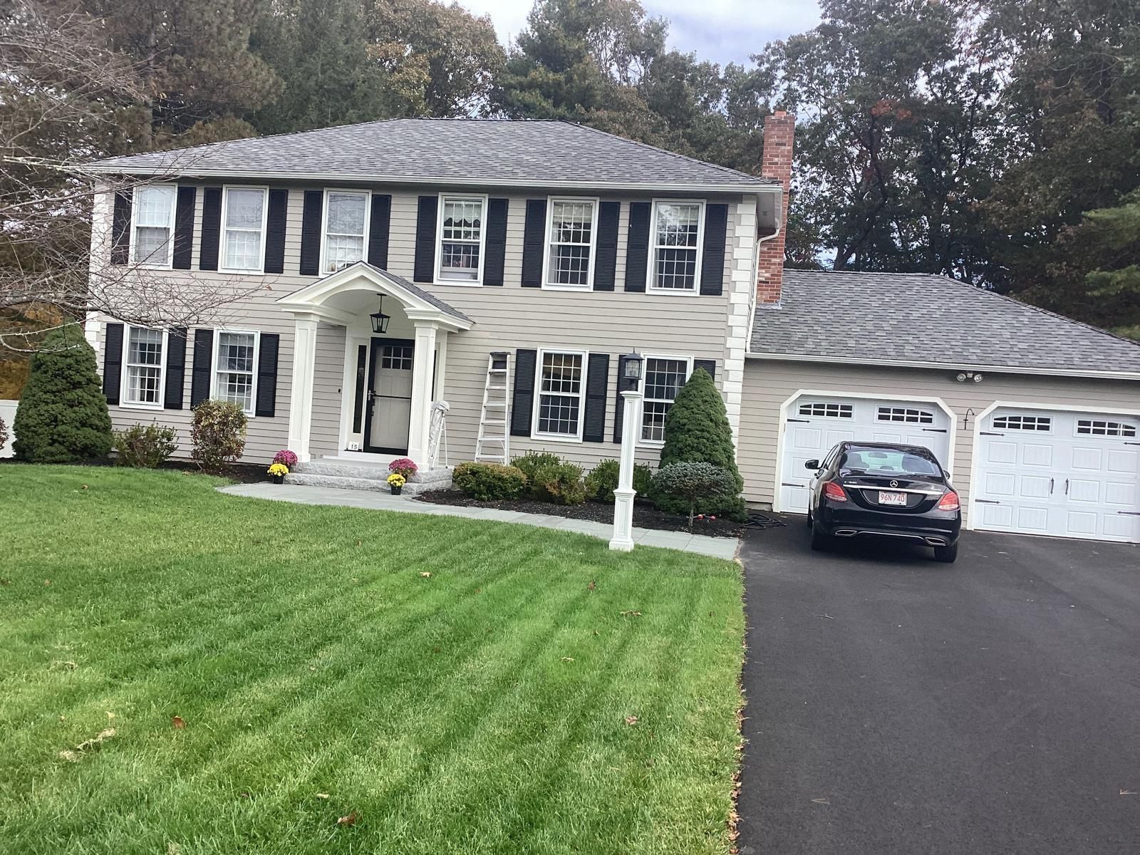 Two-story suburban house with black shutters, white trim, and a car parked in the driveway