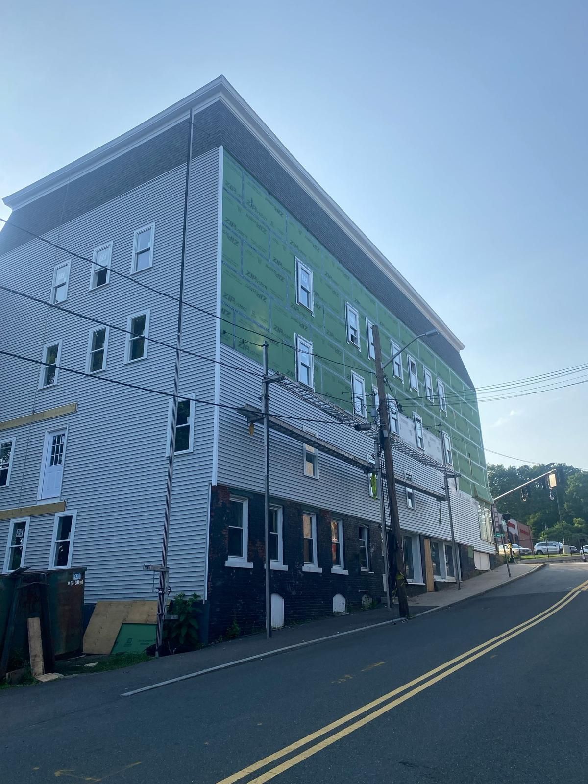 Tall green-and-gray building on a sloped street under a clear sky