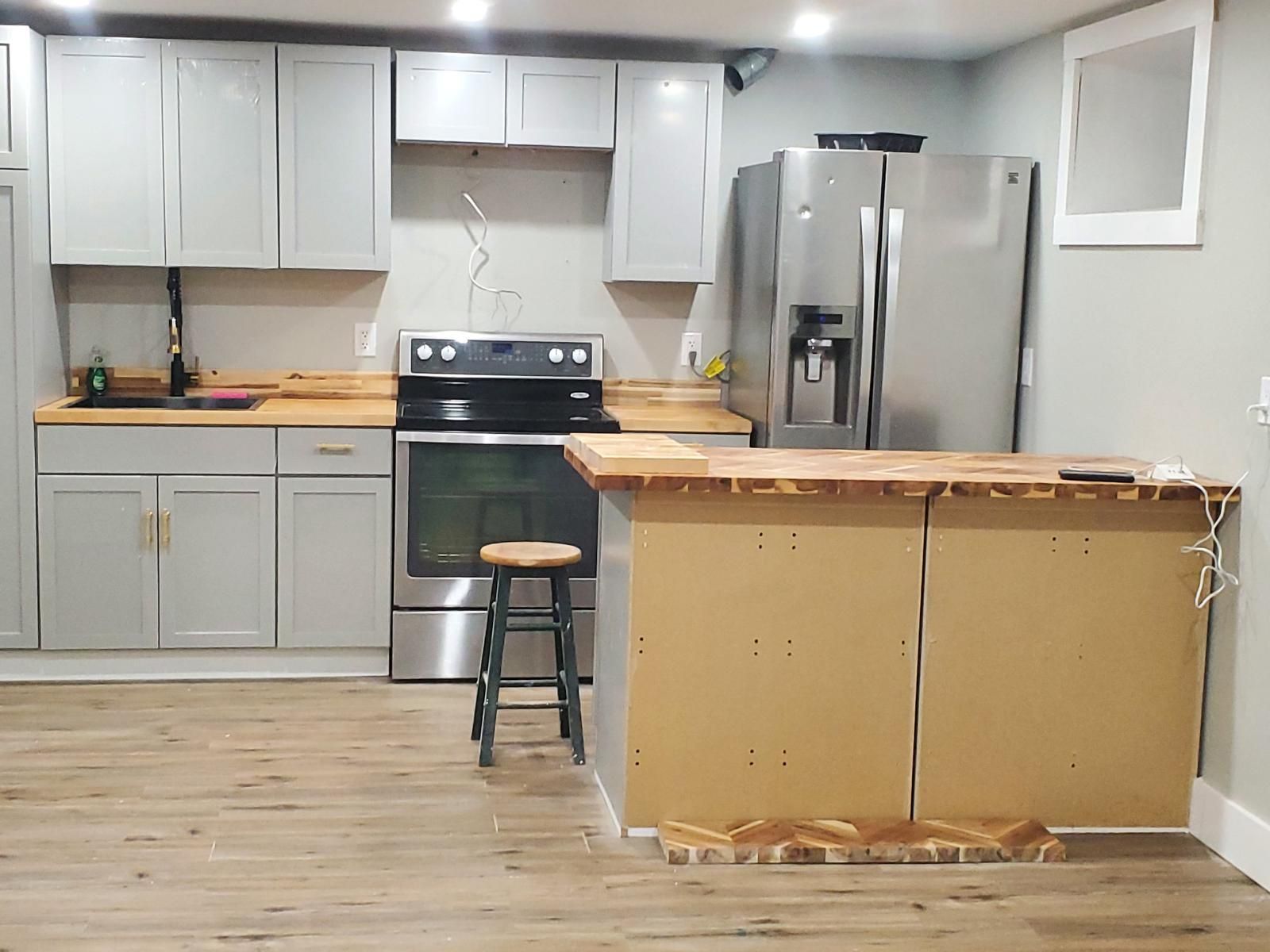 Modern kitchen with white cabinets, stainless stove and fridge, and a wooden island in the center