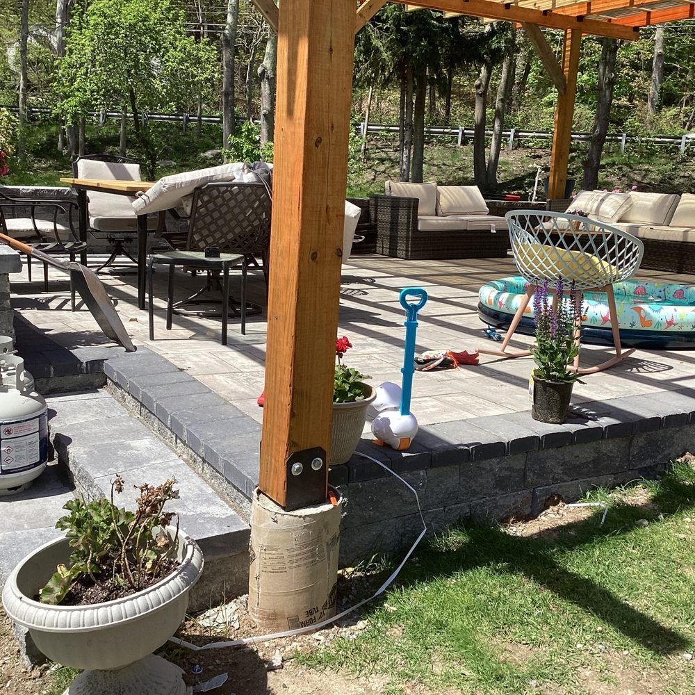 Patio with outdoor seating, potted plants, and a wooden pergola on a sunny day