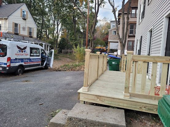 Wooden porch ramp beside a white house on a residential street, with a work van parked nearby.