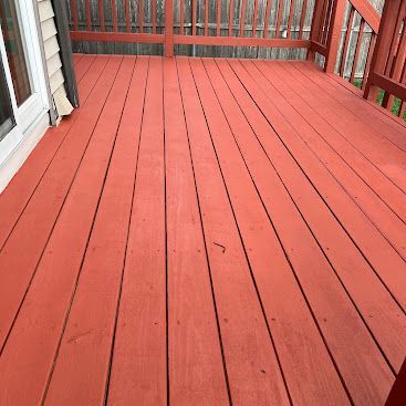 Red-painted wooden deck with railings and a screened porch on the left