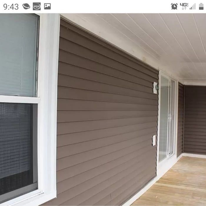 Brown-sided apartment porch with white-trimmed windows and a covered walkway