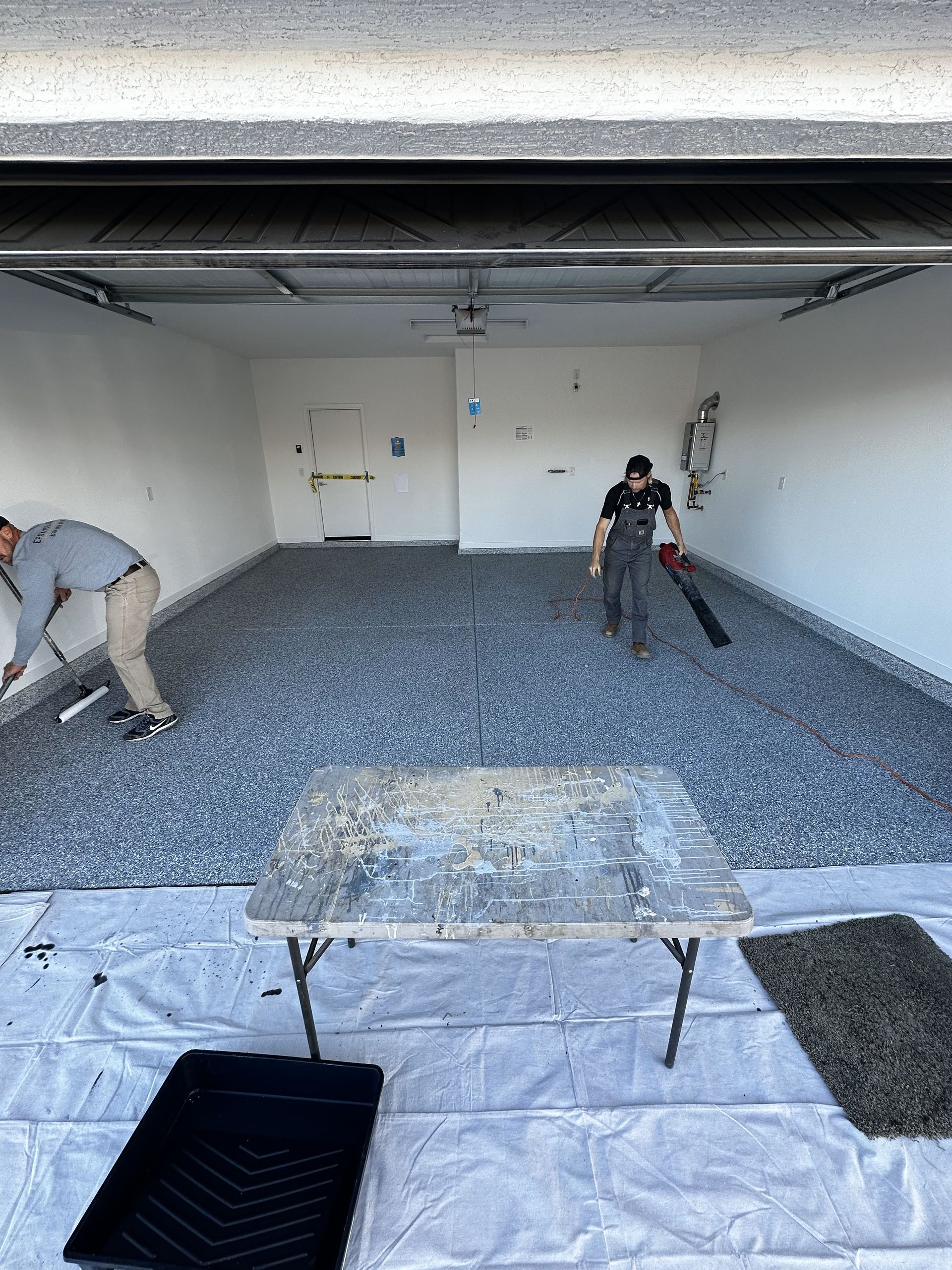 Two men are painting the floor of a garage.