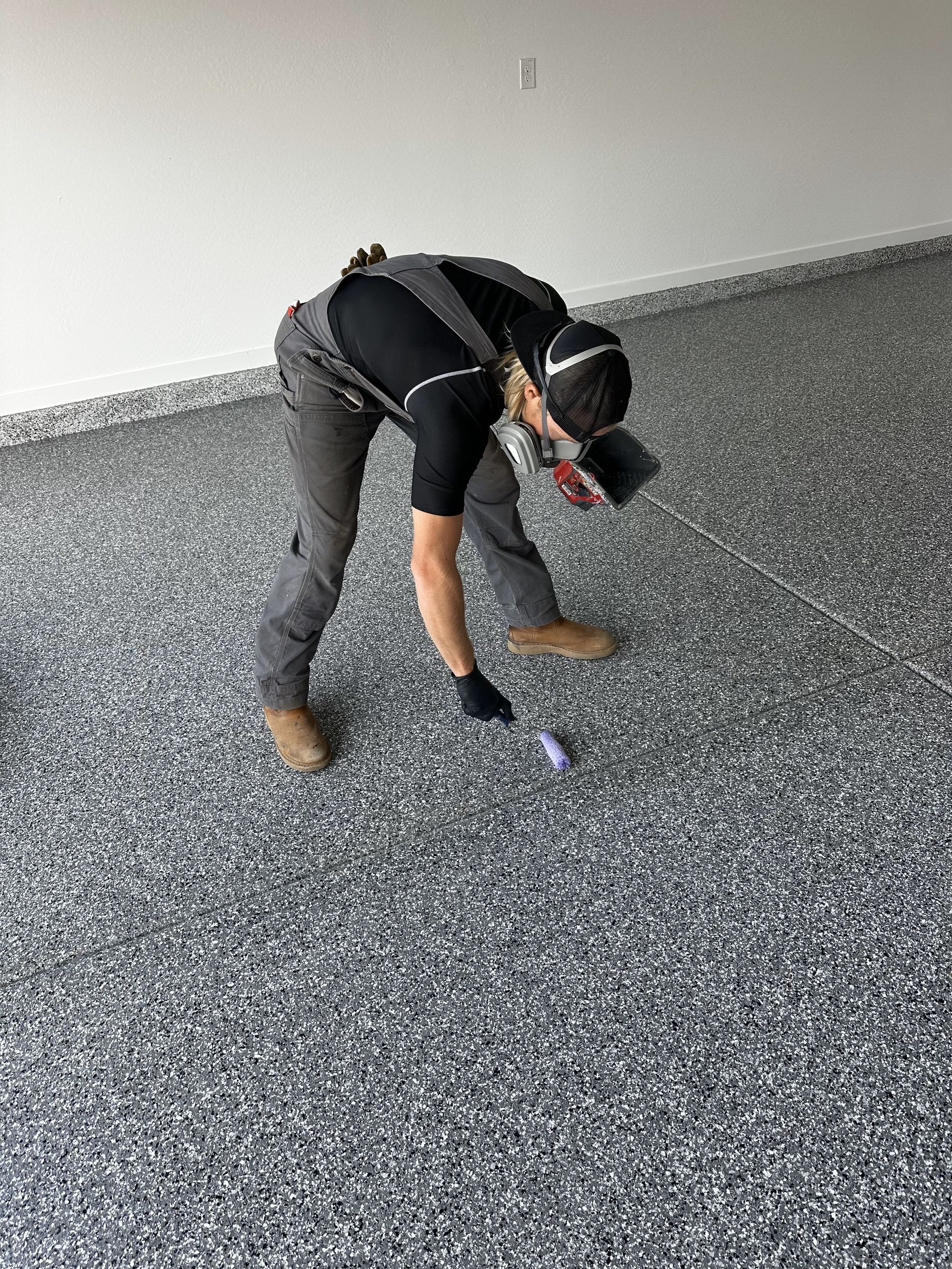 A man is kneeling down on a concrete floor in a garage.