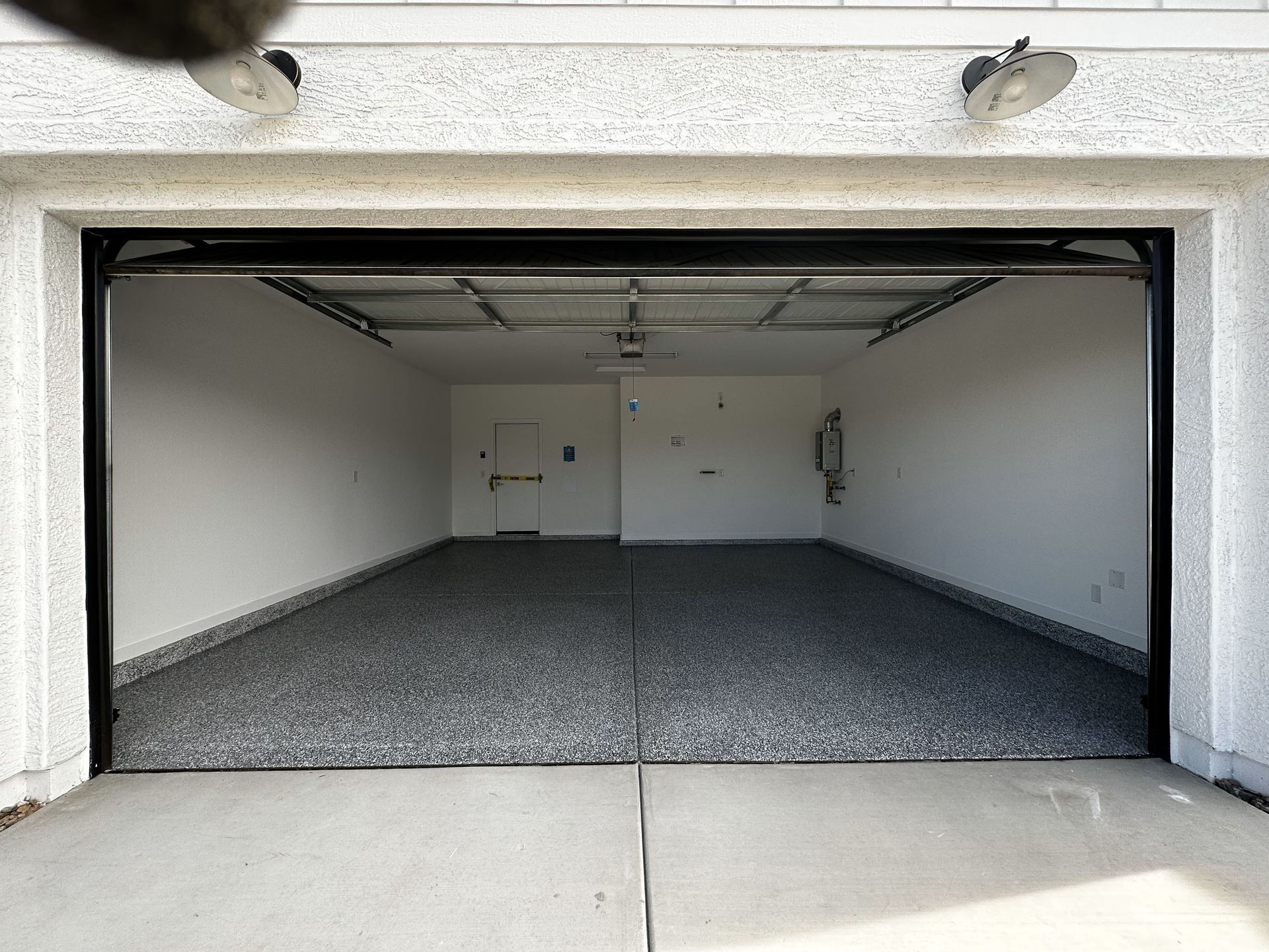 An empty garage with the door open and a gray floor