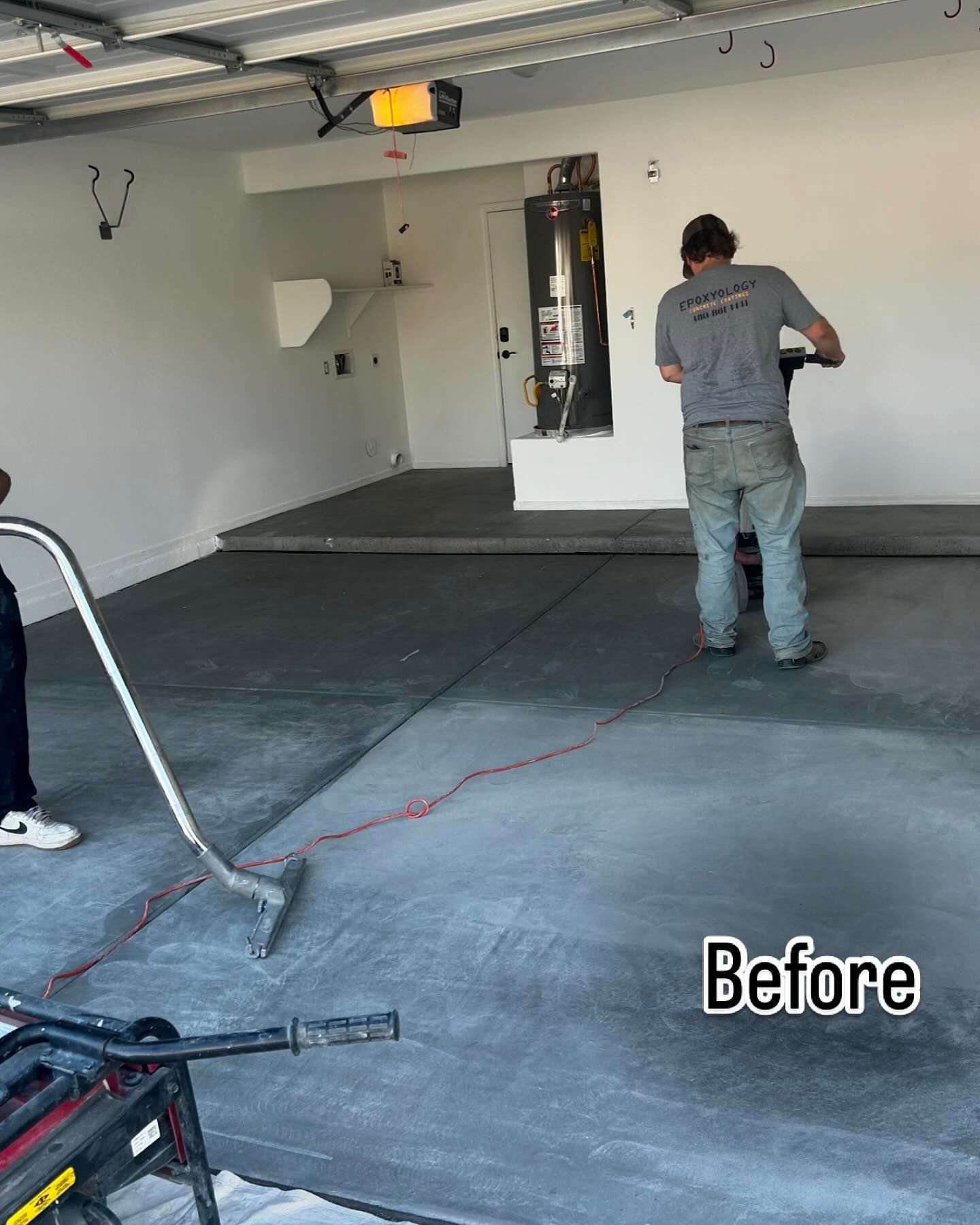 A man is cleaning a garage floor with a vacuum cleaner.