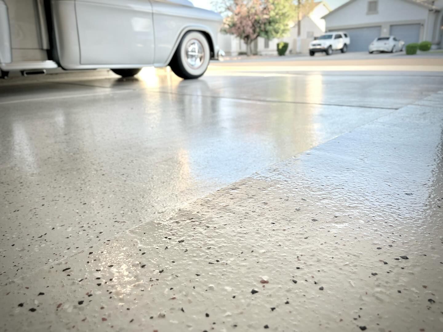 A white car is parked in a garage with a shiny concrete floor.