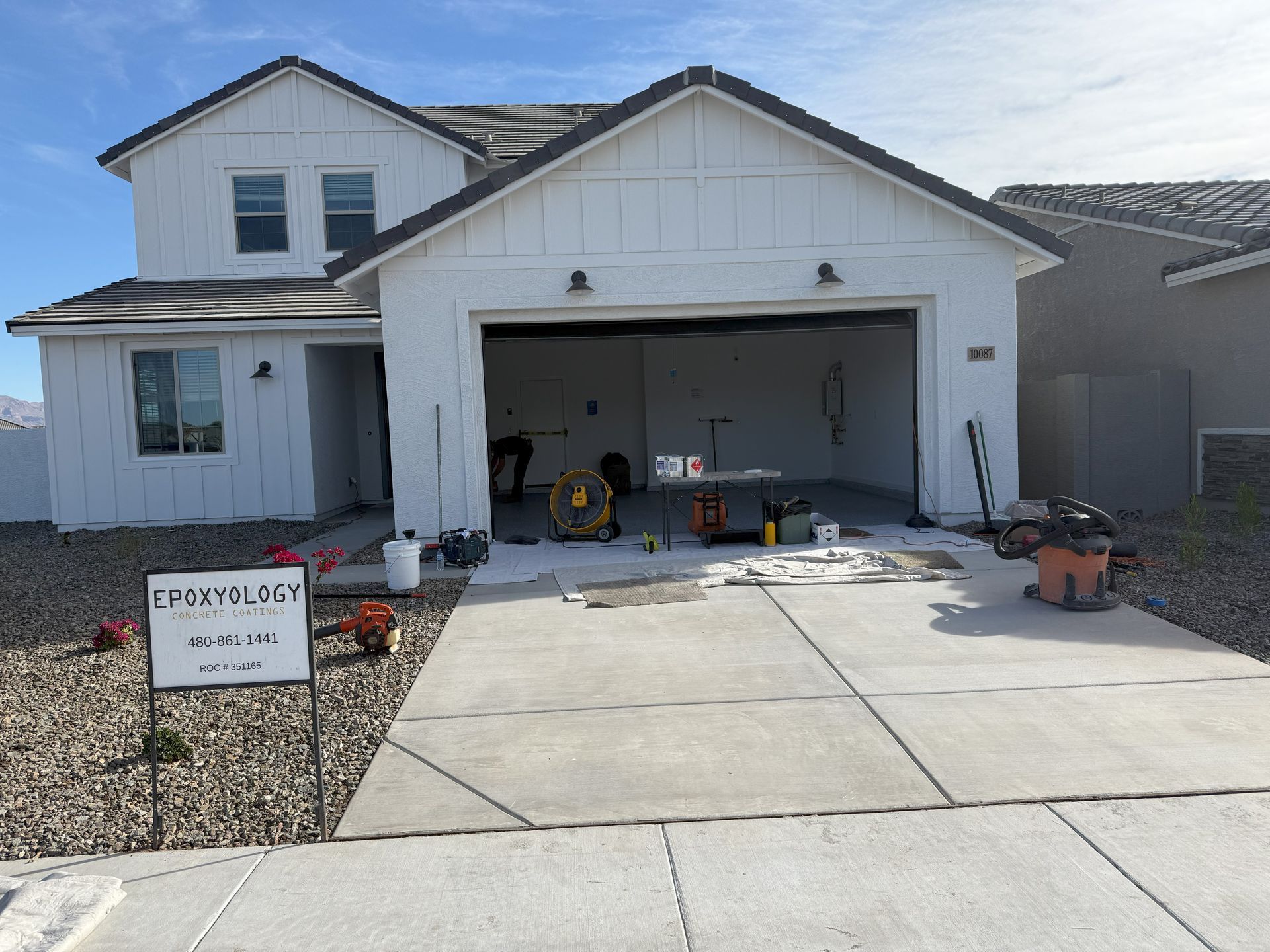 A white house with a garage and a sign in front of it.