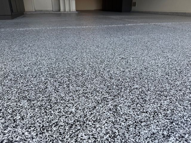 A close up of a gray and white carpeted floor in a garage.