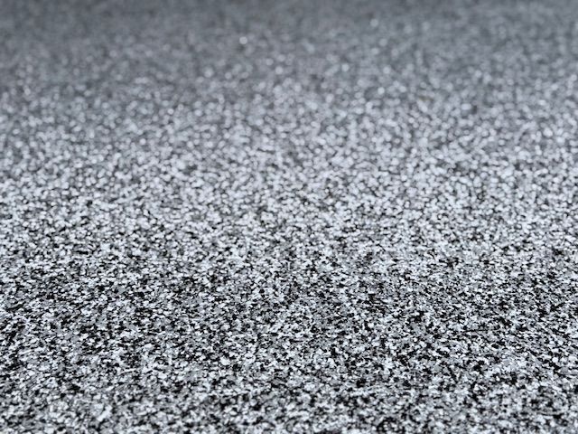 A close up of a gray carpet with a lot of small dots on it.