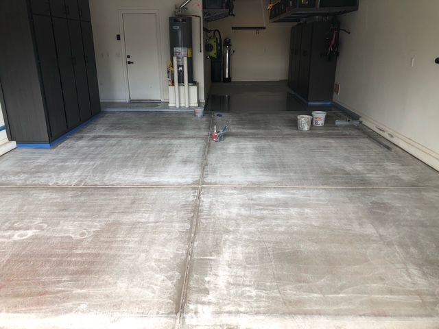 A concrete floor in a garage with buckets on it.