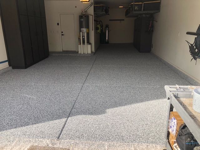 A garage with a gray floor and a black door.