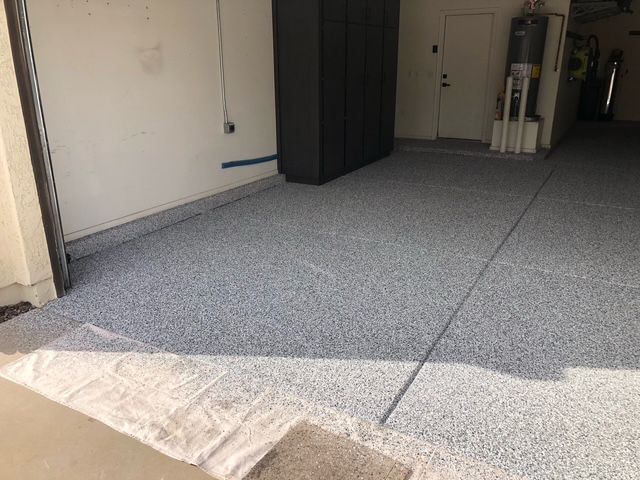 A garage with a gray floor and a black cabinet.