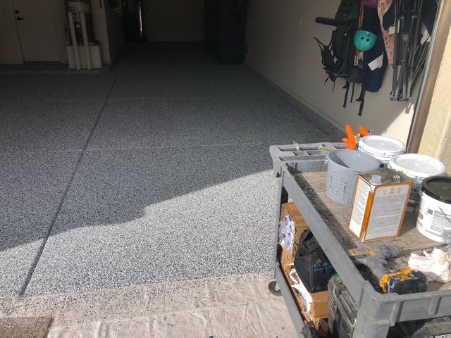 A garage with a cart filled with tools and paint.