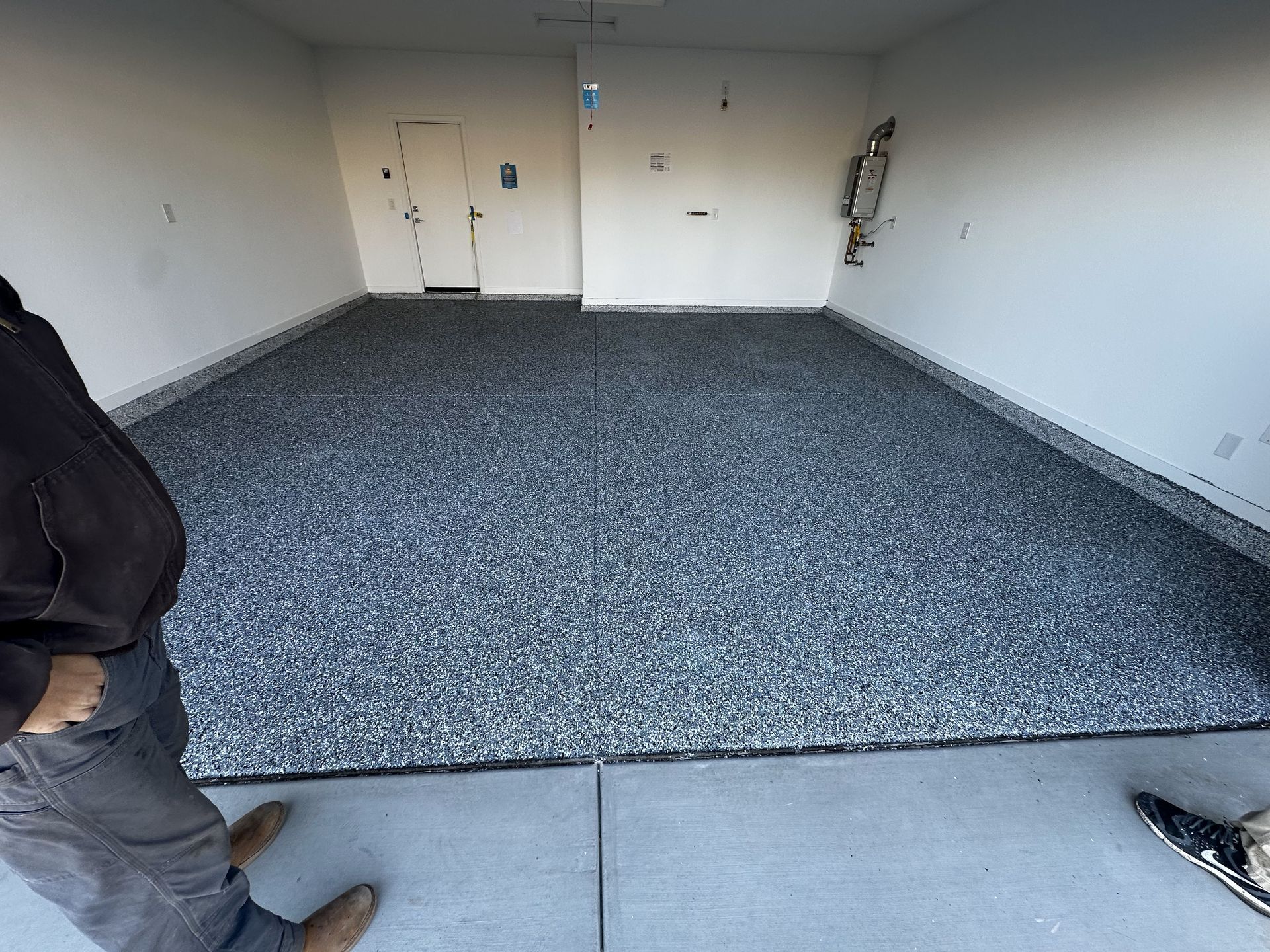 A man is standing in a garage with a gray floor