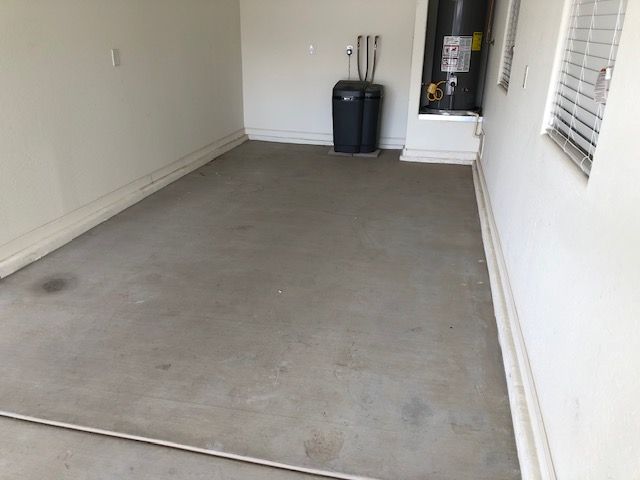 An empty room with a water heater and a trash can