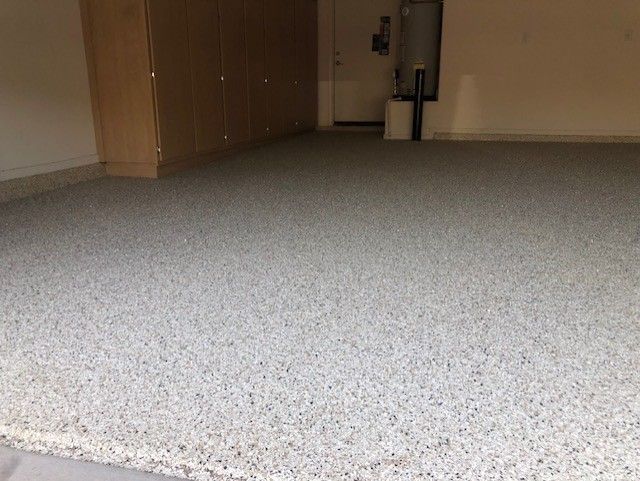 A garage with a gray carpeted floor and a door.