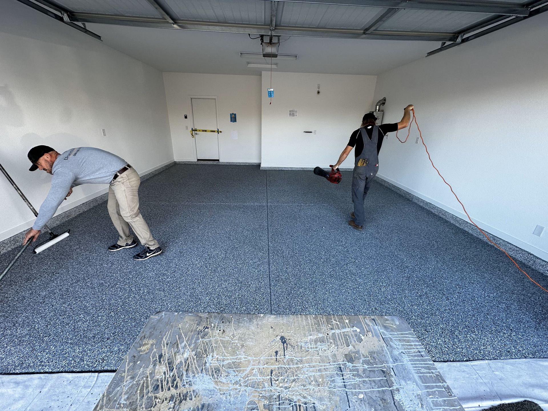 Two men are working on a garage floor.