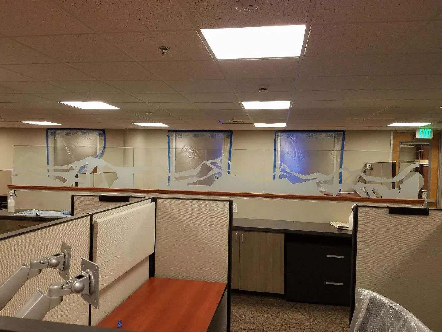 Office space with painted mountain scene on the wall, partially obscured by cubicle dividers.