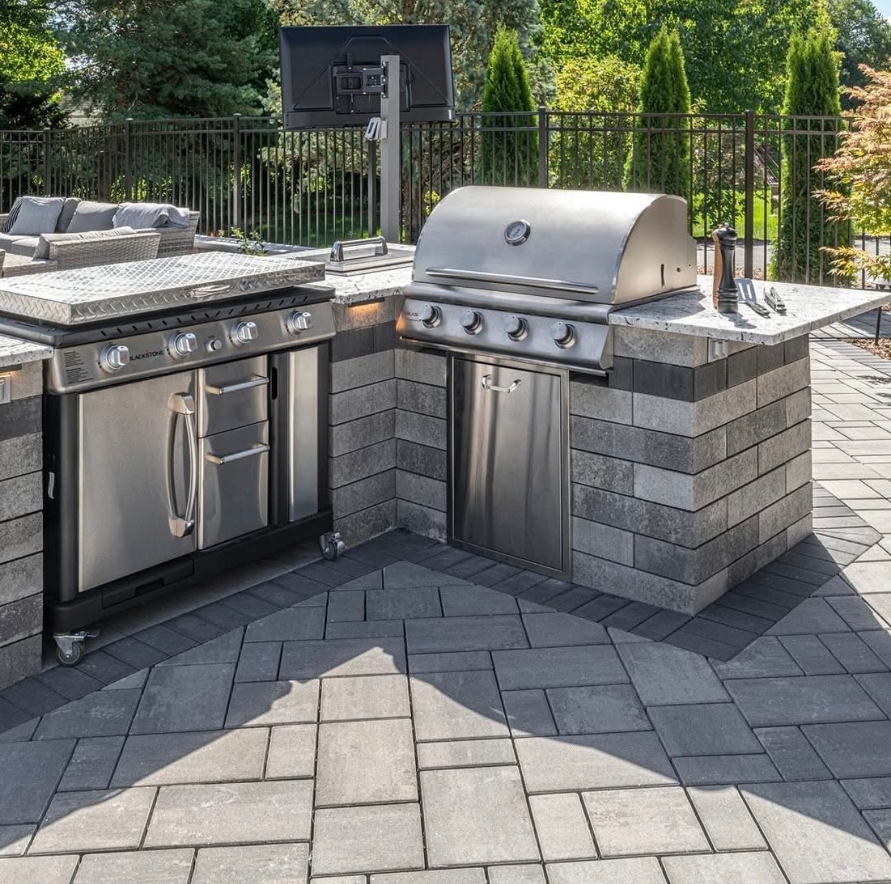 A stainless steel grill is sitting on top of a brick patio.