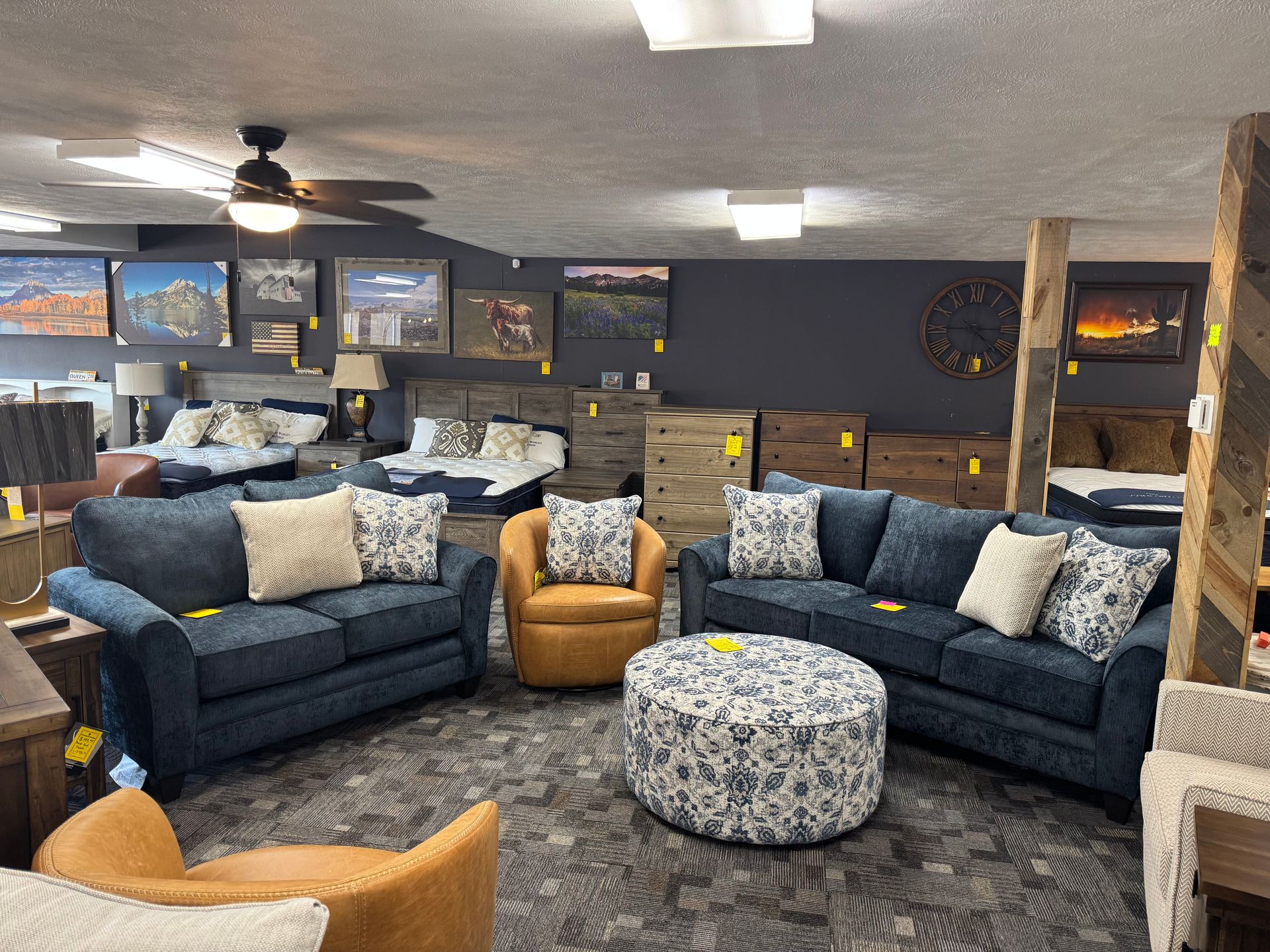 Furniture store showroom displaying sofas, chairs, ottoman, beds, and decorative wall art.