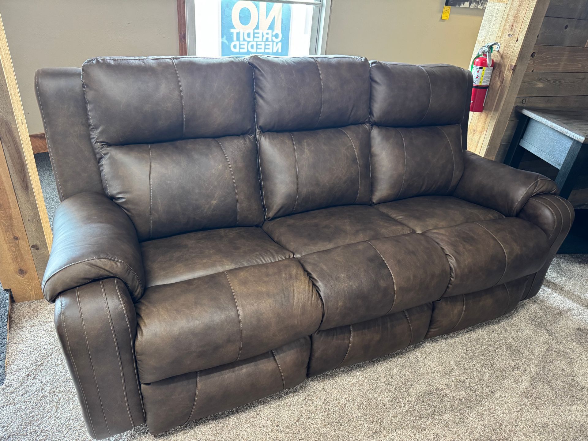 Brown leather reclining sofa in a store setting.