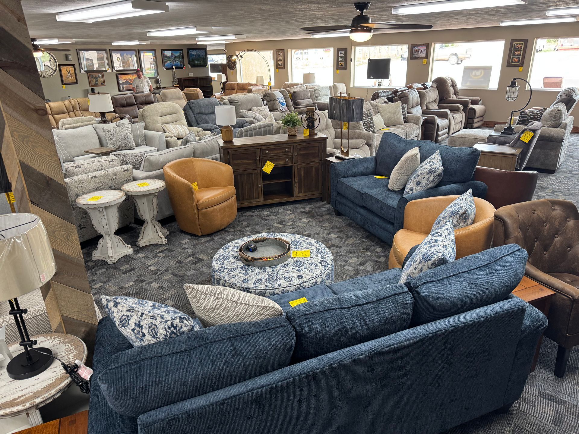 Furniture store interior with couches, armchairs, and tables. Various colors and styles on display.
