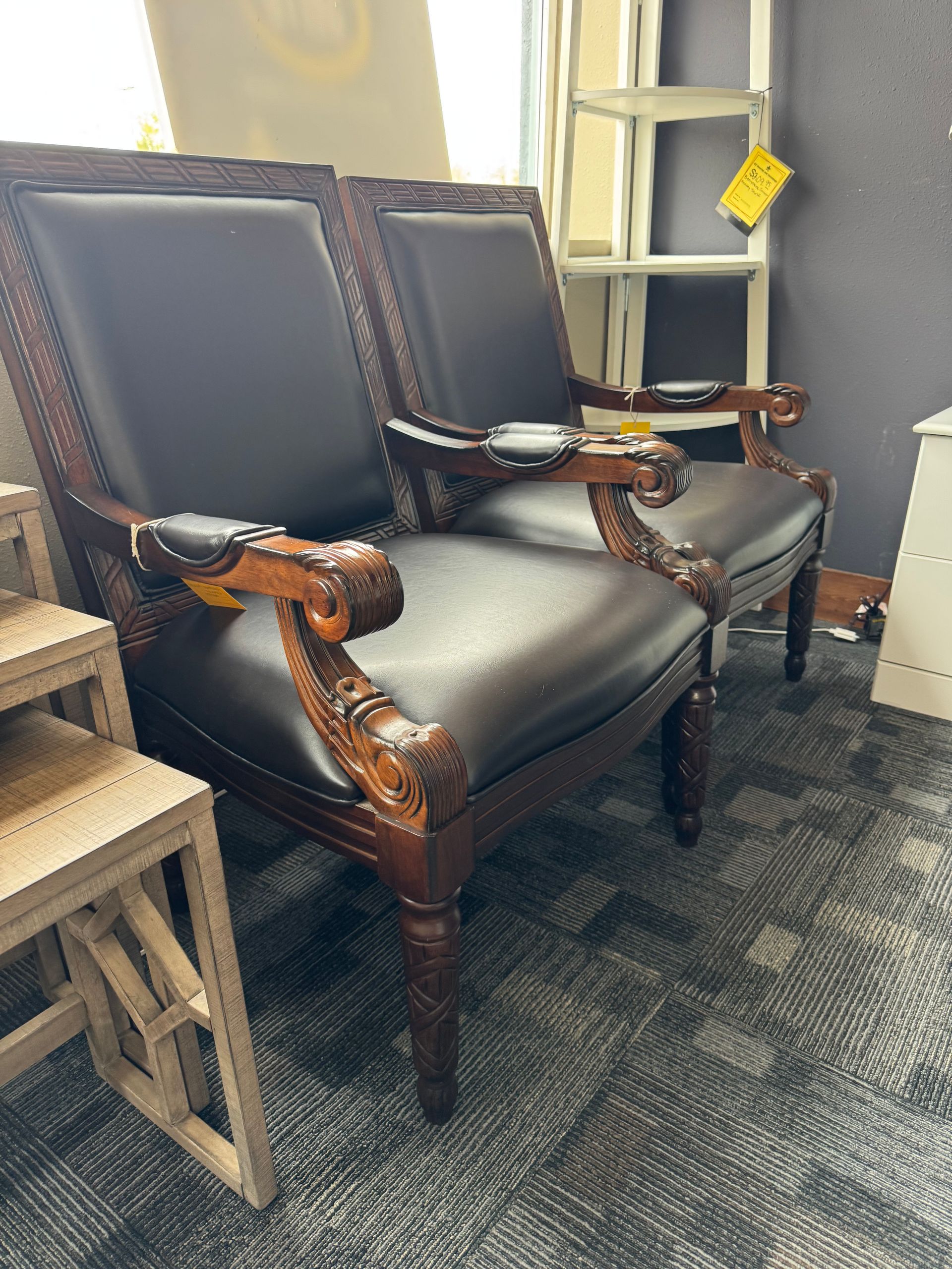 Two ornate, dark brown leather armchairs with carved wooden frames.