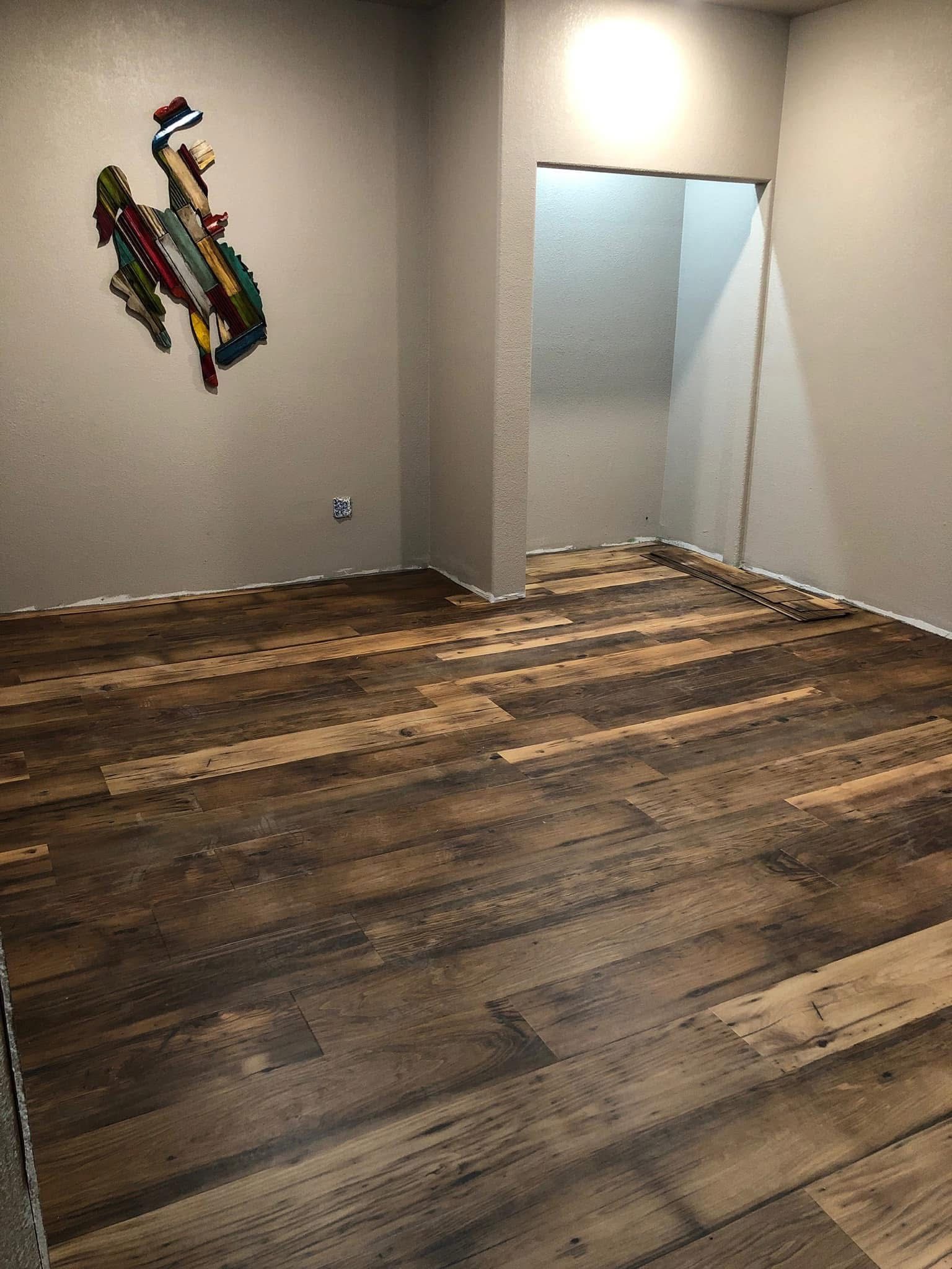 Empty room with wood-look flooring and a pixel art cowboy on the wall; doorway to the right.