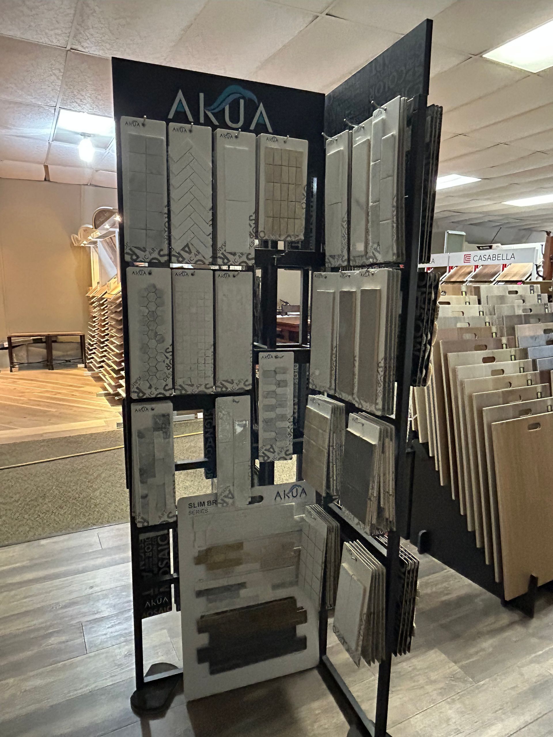 Tile samples on a display rack in a store, showcasing various colors and textures.