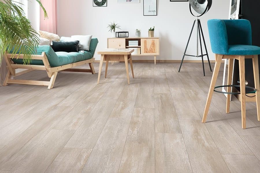 Light wood-look flooring in a living room with a turquoise couch and bar stool.