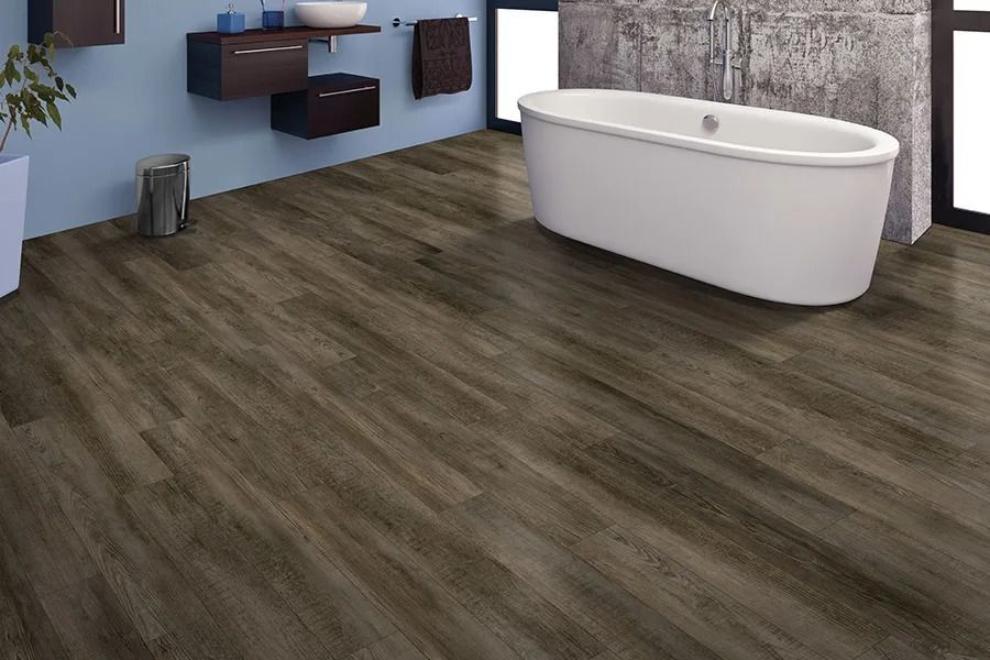 Bathroom with dark wood-look flooring, a white bathtub, and blue walls.