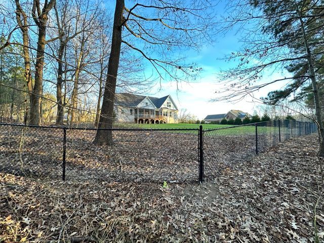 A house is behind a fence with trees in the background