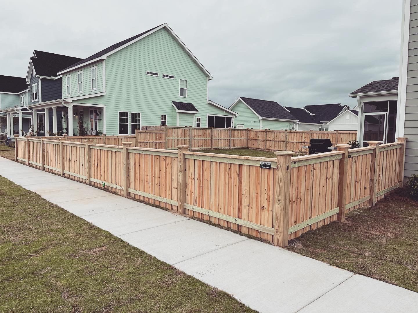 A wooden fence surrounds a yard in front of a house.