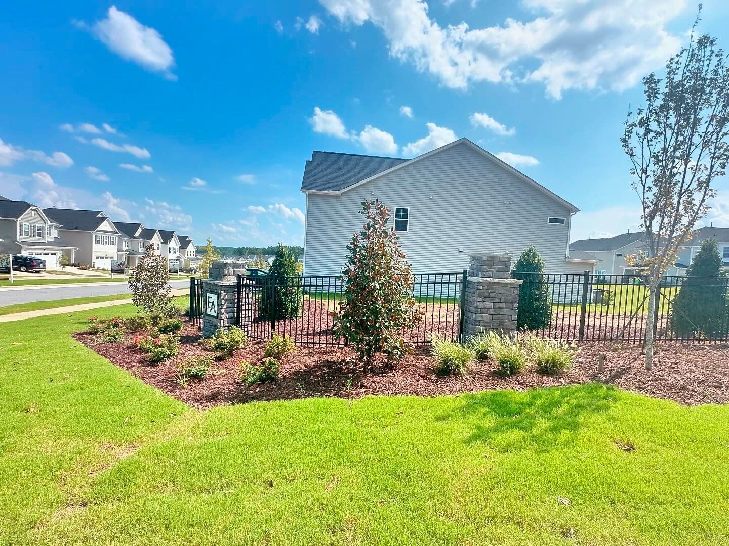 A house with a fence and a lot of grass in front of it.