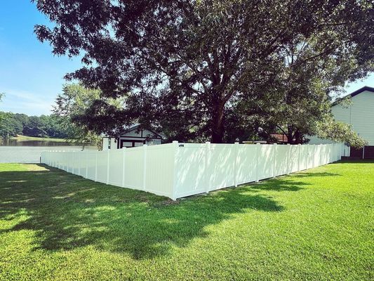 A white fence is in the middle of a lush green yard.