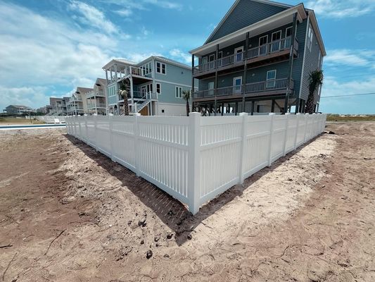 A white fence is surrounding a house in a residential area.