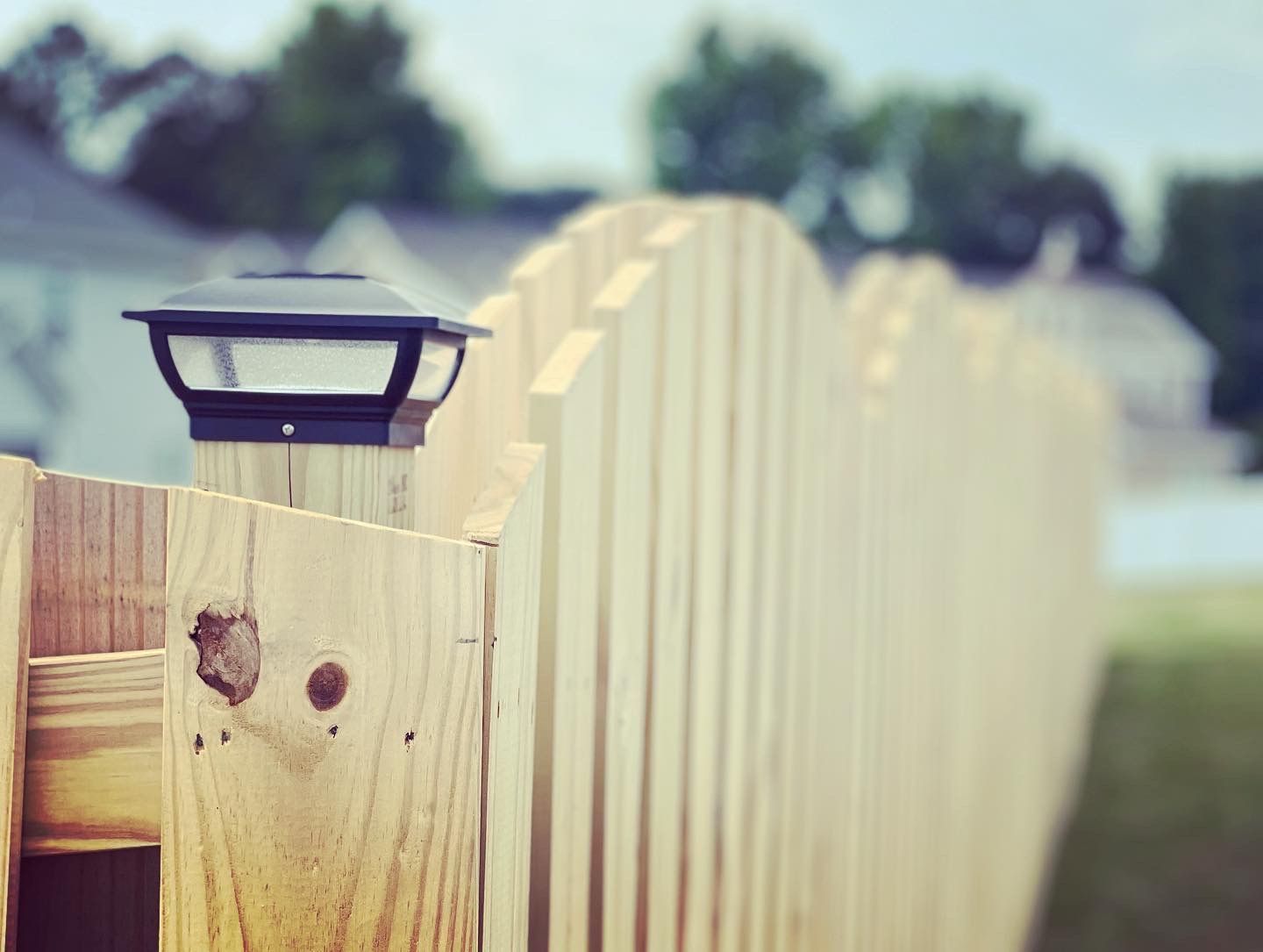 A wooden fence with a solar light on top of it.