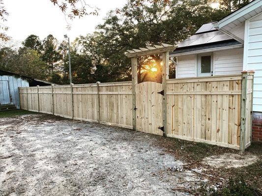 A wooden fence with a gate in front of a house.